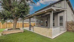 A house with a covered patio, a stone accent wall, and a wooden fence in the background. - *NEW* Modern Getaway - Houston (Houston)