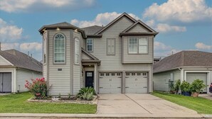 A two-story house with a garage, a front porch, and a well-maintained lawn. - *NEW* Modern Getaway - Houston (Houston)