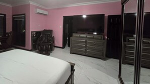 A bedroom with a bed, a TV, a dresser, and a chair. - Enjoyable apartment with AC in Kingston (Kingston)
