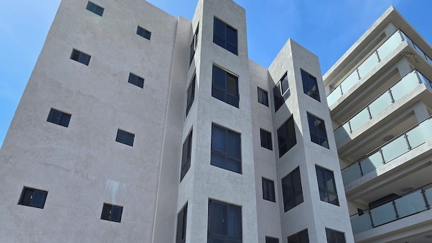 A multi-story building with a flat facade, several windows, and air conditioning units on the ground floor. - Enjoyable apartment with AC in Kingston (Kingston)