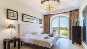 Ein geräumiges Schlafzimmer mit einem großen Bett, einer Chandelier und einem Balkon mit Blick.