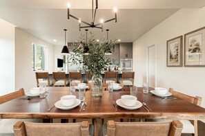 A dining area with a wooden table set for six, surrounded by chairs, with a vase of greenery in the center. - Deer Valley East Retreat | Ski, Hike & Lake Within Reach | Free Ski Shuttle (Heber City)