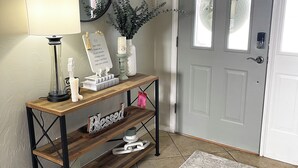 Een inkomhal met een houten console tafel, een spiegel, een potplant, een bord en een deur.