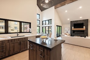 A modern kitchen with dark wood cabinets, a central island, and large windows. - Old Town Black Diamond - Park City House above Main Street / Skiing + Hot Tub (Park City)