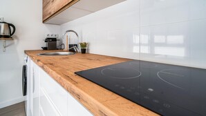 Una cocina moderna con encimera de madera, pileta de acero inoxidable y cocina por inducción negra.