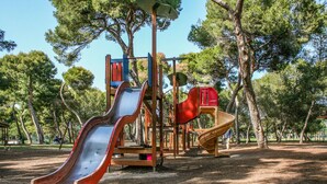 Un parque infantil con toboganes y estructuras para escalar, rodeado de árboles.