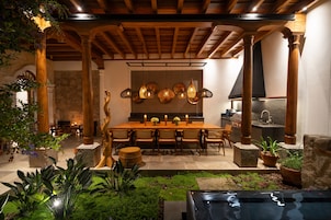 Comedor con mesa de madera, sillas, lámparas colgantes y pared de piedra.