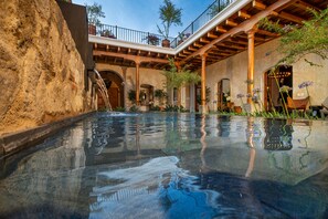 Ein Pool mit einer Steinmauer und einer Holzpergola.