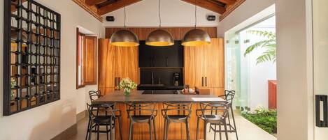 A modern kitchen with a large island, wooden cabinets, and pendant lighting.