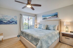 Un dormitorio con cama, mesitas de noche, ventilador de techo y obras de arte en las paredes.