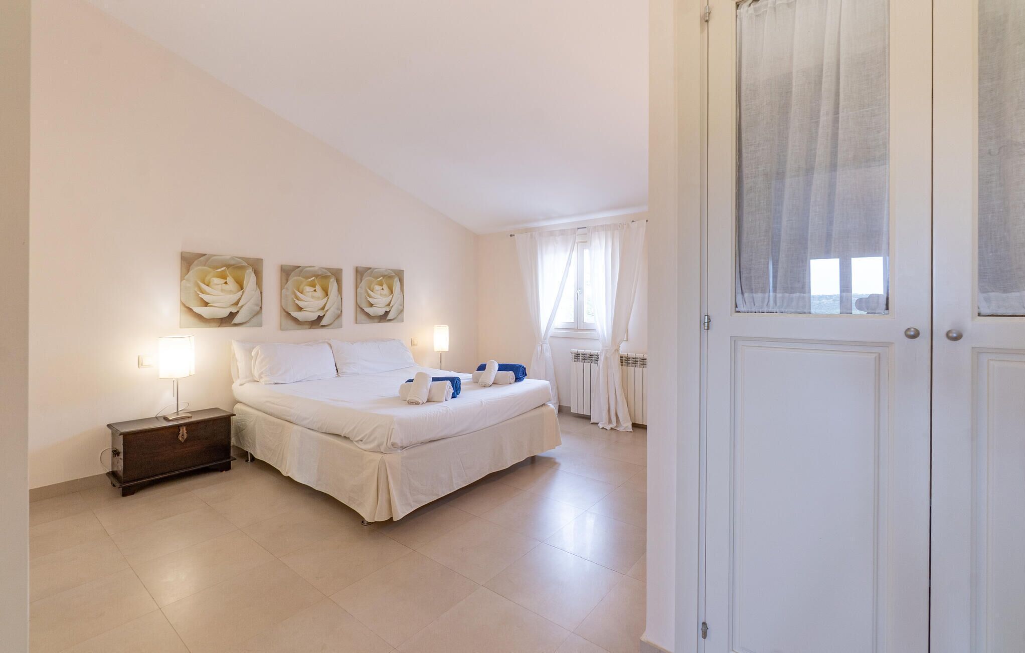 A bedroom with a bed, bedside tables, and a window with curtains.