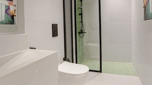 A modern bathroom with a white toilet, a glass-enclosed shower, and a wooden vanity. - Two Bedroom Colorful & Exotic Flat in Alrabie (Riyadh)