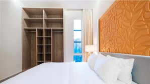 Habitación de hotel con una cama grande, un armario con estantes múltiples, una ventana con vistas y un panel decorativo en la pared.