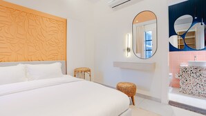 A modern hotel room with a large bed, a wall-mounted air conditioner, a round mirror, and a bathroom with a tiled floor and a sink. - Three Bedroom Colorful & Exotic Flat in Alrabie (Riyadh)
