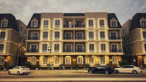 A multi-story hotel with a symmetrical facade, multiple balconies, and a central entrance. - Three Bedroom Colorful & Exotic Flat in Alrabie (Riyadh)