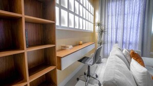 Una sala de estar moderna con una estantería de madera, un escritorio con una silla y un sofá con cojines.