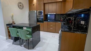 Una cocina moderna con armarios de madera, encimera de mármol negro y horno empotrado.