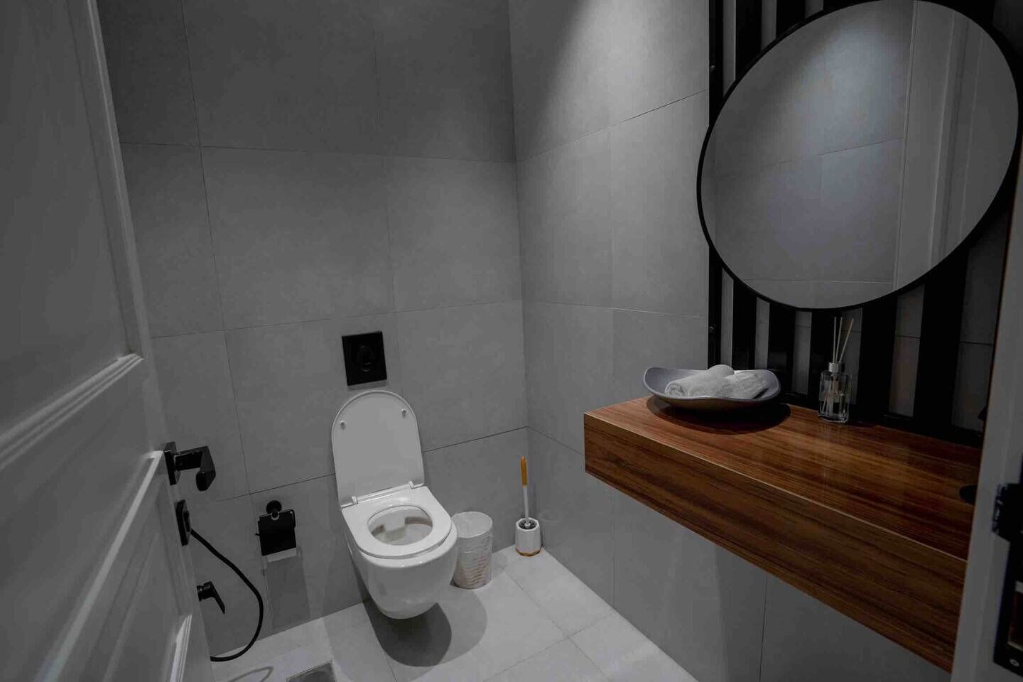 Un baño moderno con inodoro, lavamanos con encimera de madera y espejo.