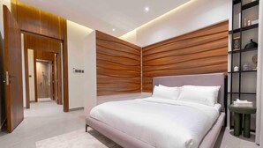 Une chambre moderne avec un grand lit, un mur recouvert de panneaux en bois et une petite table de chevet.