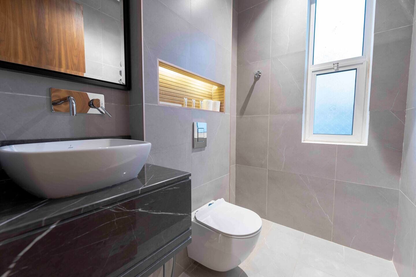 Un bagno moderno con un ampio lavandino bianco, un WC e una zona doccia.