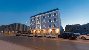 Un hôtel à plusieurs étages au design moderne, doté d’un parking pouvant accueillir plusieurs voitures.