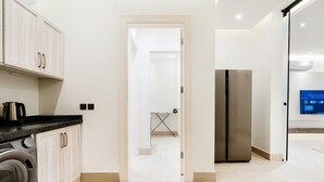 A modern kitchen with a washing machine, a stainless steel refrigerator, and a flat-screen TV on the wall. - Three BR Spacious & Luxurious Flat in Hittin (Riyadh)