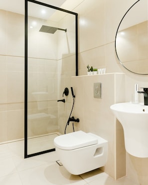 A modern bathroom with a glass-enclosed shower, a white toilet, and a sink with a mirror above it. - Three BR Spacious & Luxurious Flat in Hittin (Riyadh)