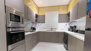A modern kitchen with stainless steel appliances, a built-in oven, and a dishwasher. - Apartment Luxurious and Modern Design in Alwadi Xl (Riyadh)