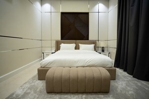 Une chambre moderne avec un grand lit, des tables de chevet et un panneau décoratif mural.