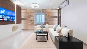 A modern living room with a sofa, coffee table, and TV mounted on the wall. - Stylish & Relaxing Flat in Alwadi Vll (Riyadh)