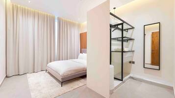 Una camera da letto moderna con un letto, un'ampia finestra con tende, un armadio a muro e uno specchio sulla parete.