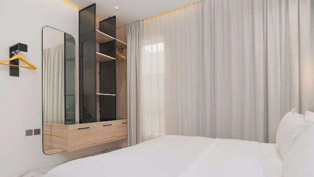 A modern bedroom with a large bed, a built-in wardrobe, and a mirror. - Luxurious 2-br Flat With Relaxation Space lll (Riyadh)