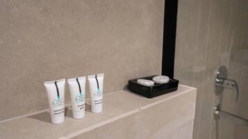 A bathroom shelf with three bottles of shower gel and two round containers, likely for body lotion or cream.