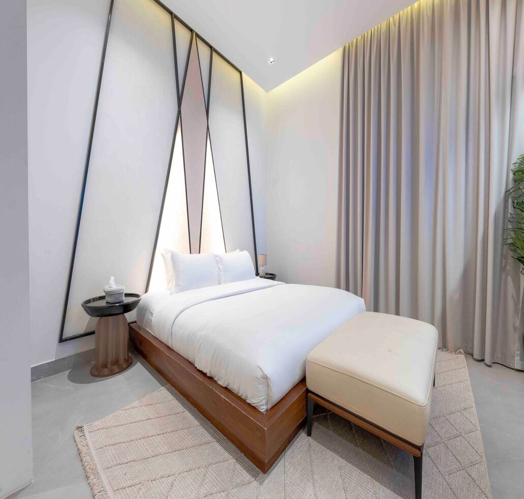 A modern bedroom with a large bed, bedside tables, and a view of the city.