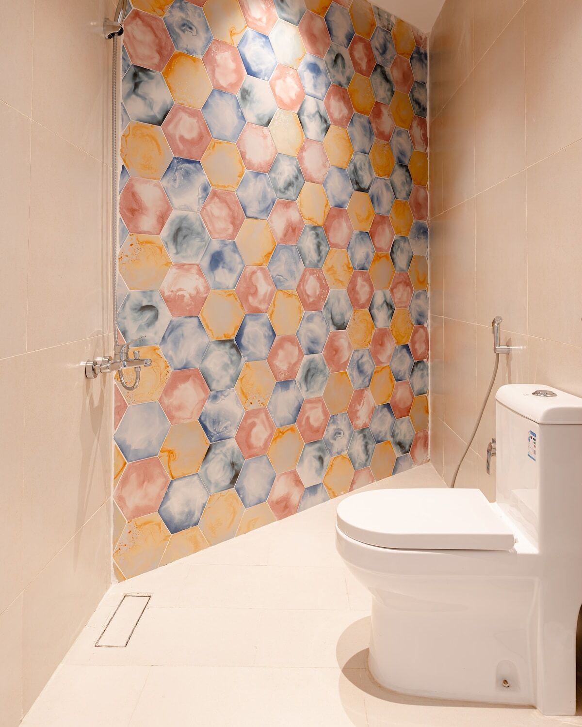 A bathroom with a white toilet, a shower with a glass door, and a wall with a hexagonal tile pattern.