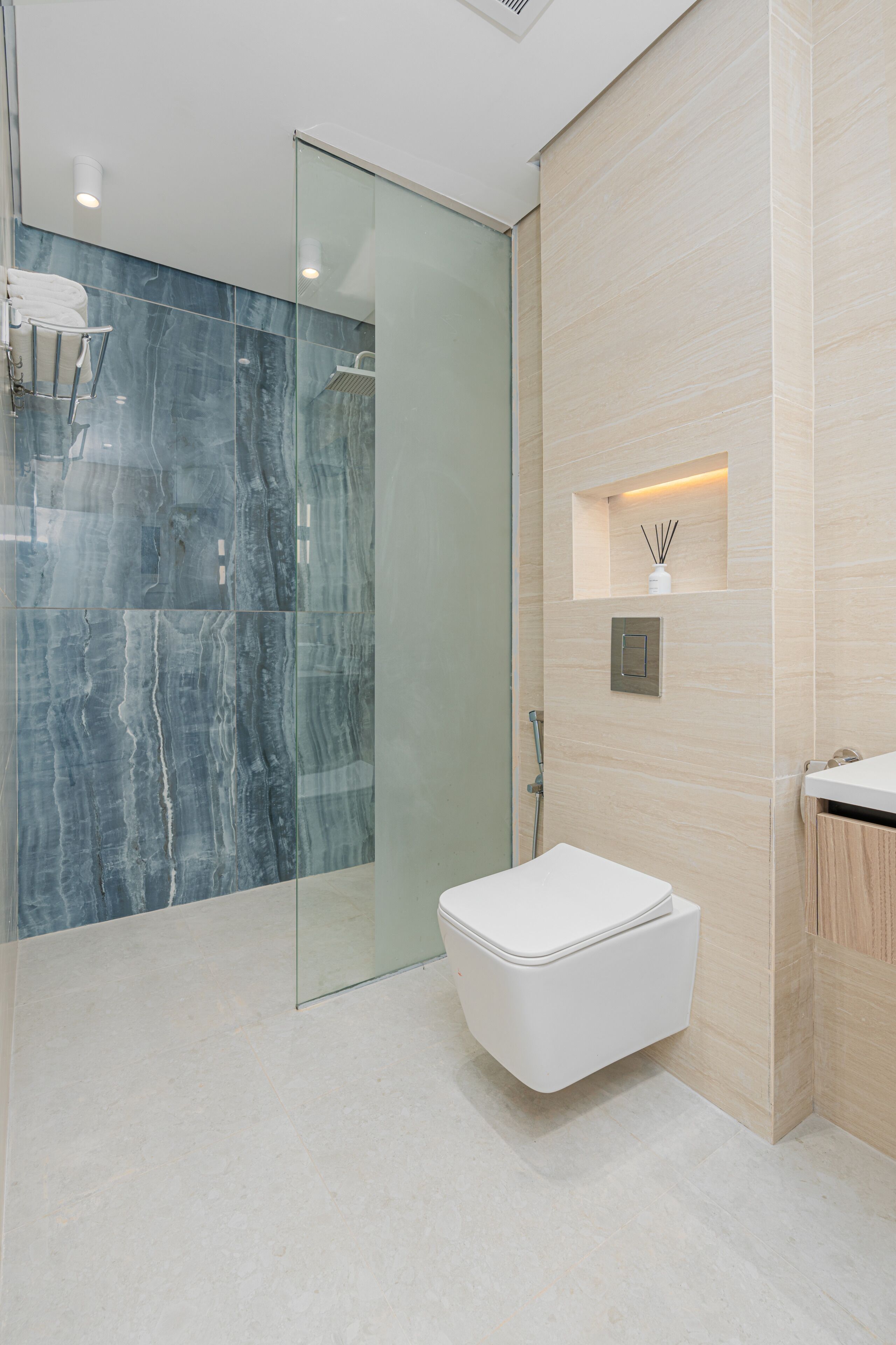 A modern bathroom with a glass shower enclosure, a white toilet, and a wooden vanity.