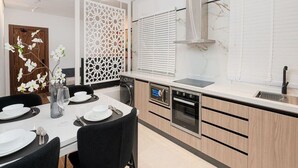 A modern kitchen with a dining area, featuring a built-in oven, a microwave, and a stainless steel range hood.