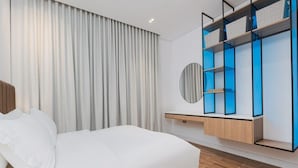 A modern bedroom with a large bed, a wooden floor, a built-in wardrobe with blue lighting, and a round mirror.