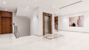 A spacious lobby with a marble floor, a wooden door, an elevator, and a staircase. - Cozy 1-br Apartment in Almughrizat (Riyadh)