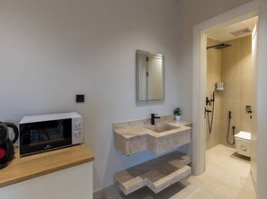 A modern bathroom with a freestanding sink, a mirror, and a shower area. - Modern Studio & Shared Garden in Prime Location (Madinah)