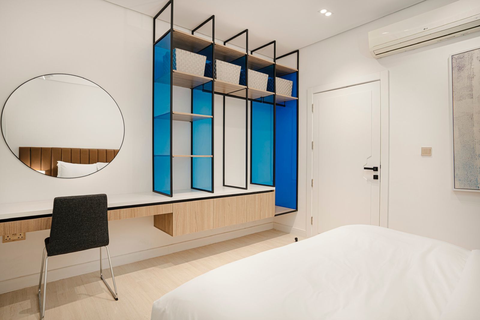 A modern bedroom with a bed, a desk, and a wardrobe with blue accents.