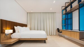 A modern hotel room with a bed, bedside table, lamp, and a desk with a chair. - Stylish and Cozy Flat in Almughrizat (Riyadh)
