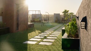 Eine moderne Außenpatio mit Kunstgrasanlage, Pflastersteinen und Topfpflanzen.