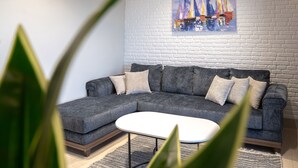 Ein modernes Wohnzimmer mit einem grauen Modulsofa, einem weißen Couchtisch und einem Gemälde von Segelbooten an der Wand.