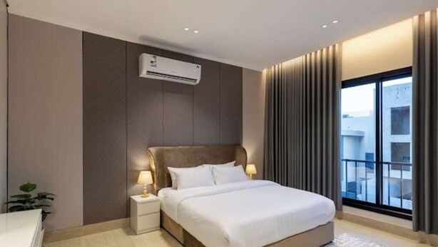 Ein modernes Hotelzimmer mit einem großen Bett, Nachttischlampen, einer Klimaanlage, Blick ins Freie und einem Balkon.
