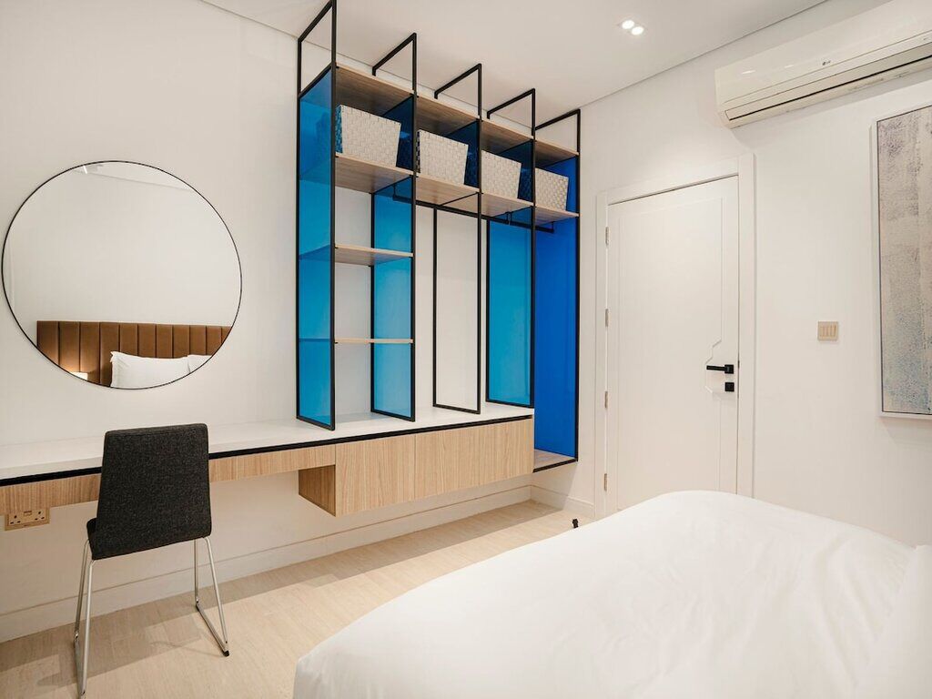 A modern bedroom with a bed, a desk, and a built-in wardrobe with blue accents.