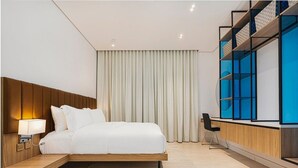 A modern hotel room with a bed, bedside table, lamp, and a desk with a chair. - Elegant & Cozy Flat in Almughrizat (Riyadh)