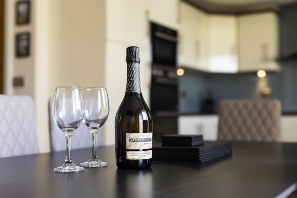 A bottle of wine and two glasses on a table in a modern kitchen setting.