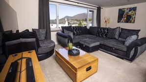 Una sala de estar moderna con un sofá seccional, una mesa de centro de madera y vistas a las montañas.