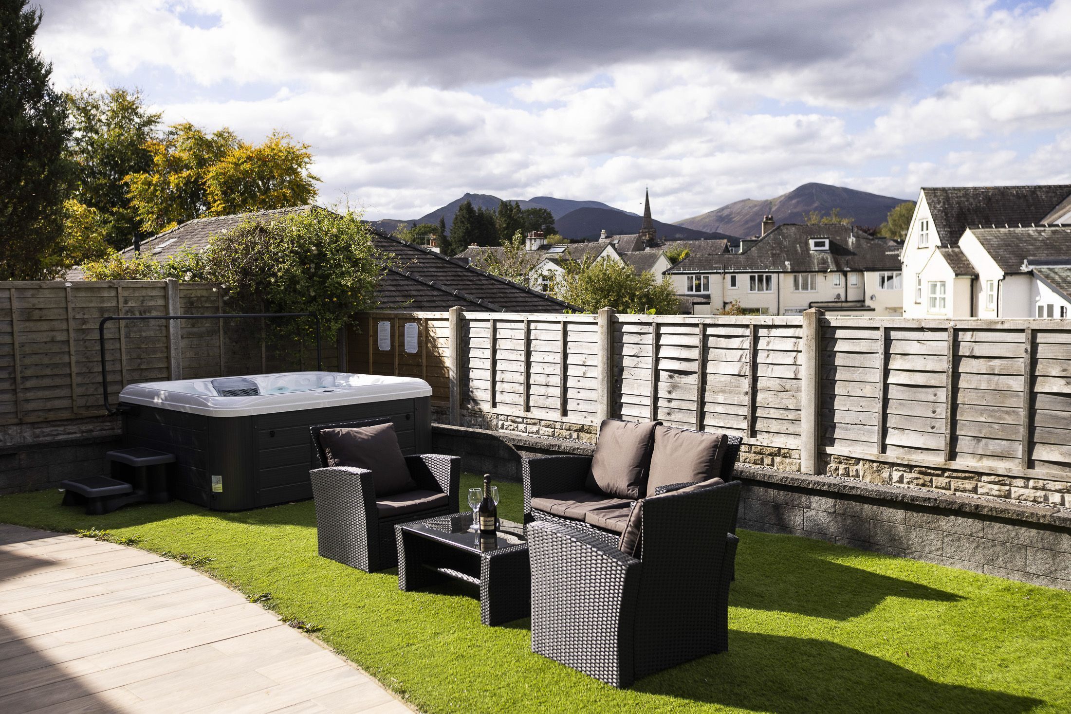 A patio with outdoor furniture, a hot tub, and a view of houses and mountains.